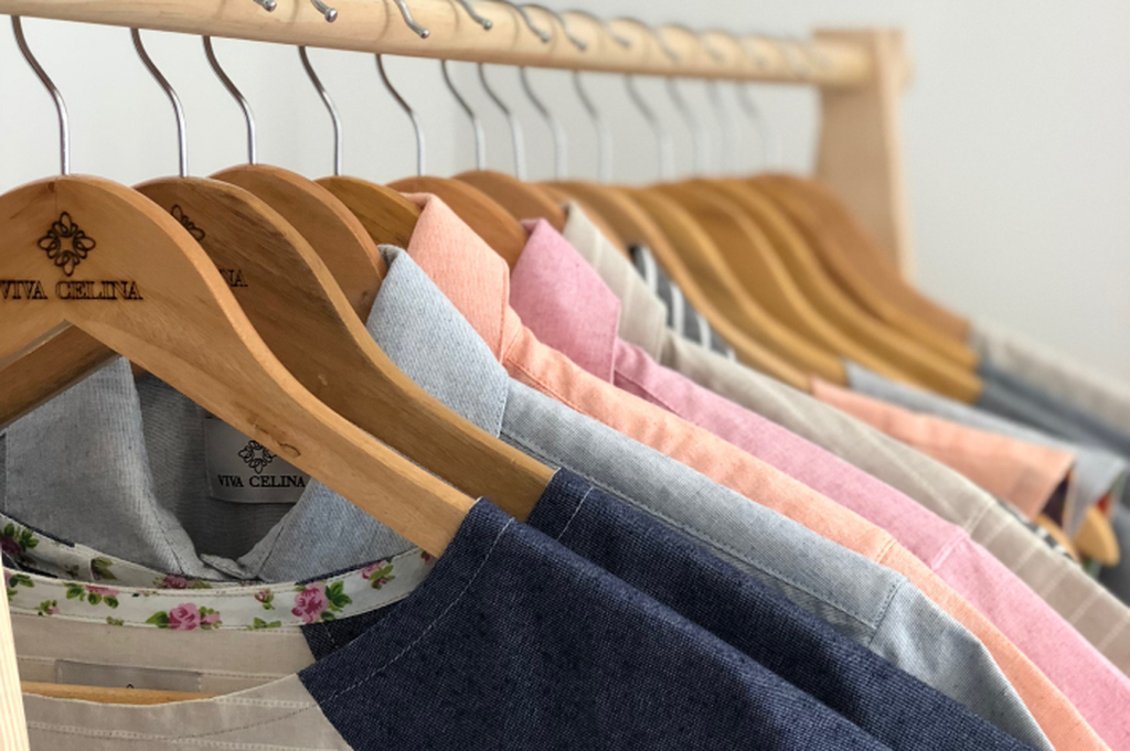 Cabide de roupas em uma loja com diversas camisetas penduradas.